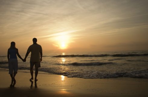 Couple walking on the beach at sunset