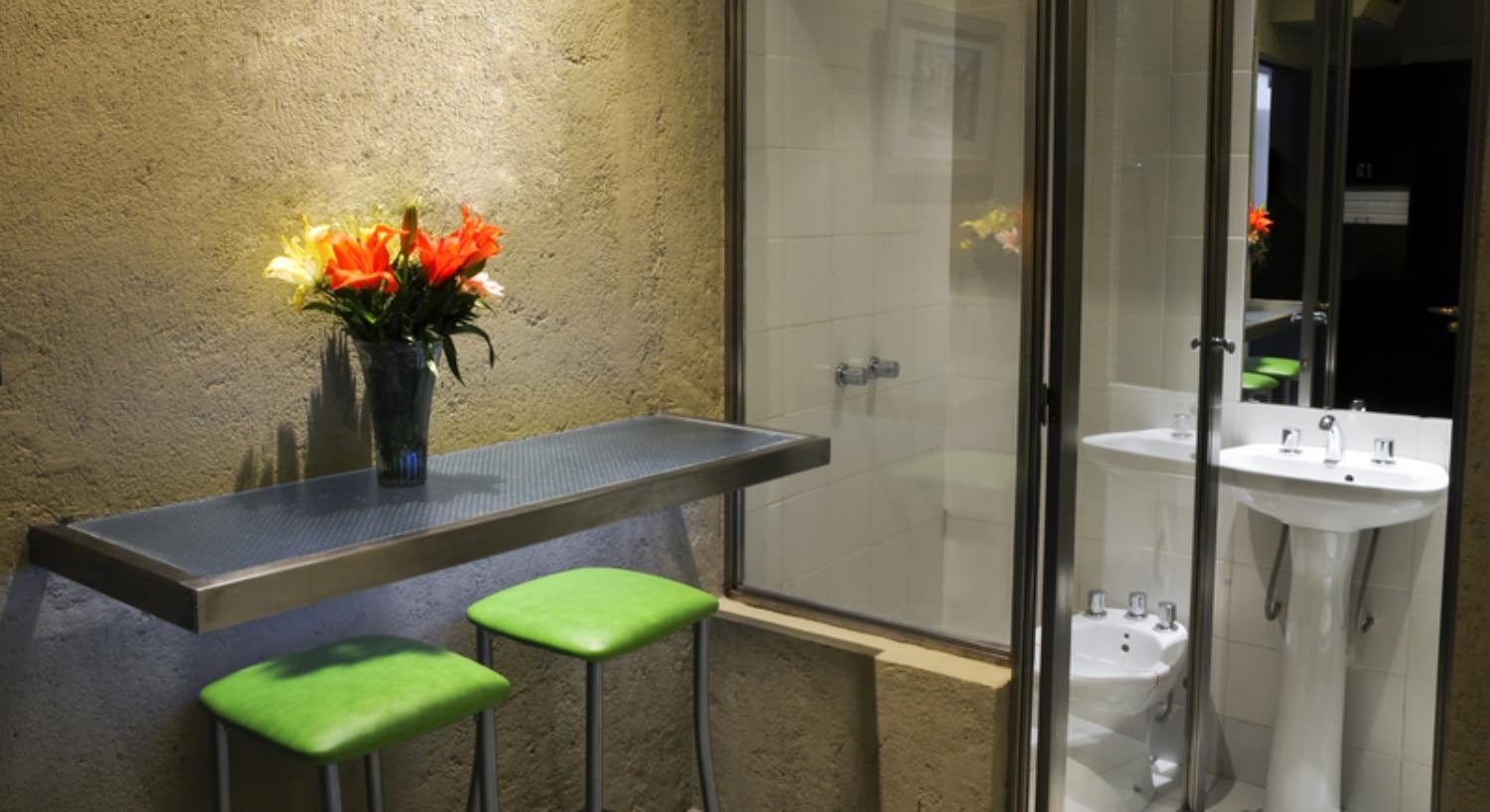 Sitting area with green cushioned bar stools and view into bathroom