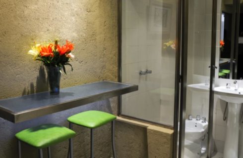 Sitting area with green cushioned bar stools and view into bathroom