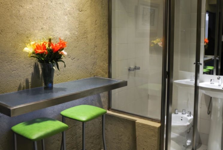 Sitting area with green cushioned bar stools and view into bathroom