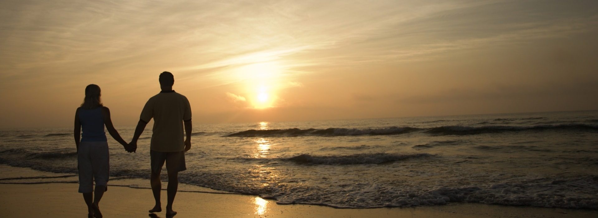 Couple walking on the beach at sunset