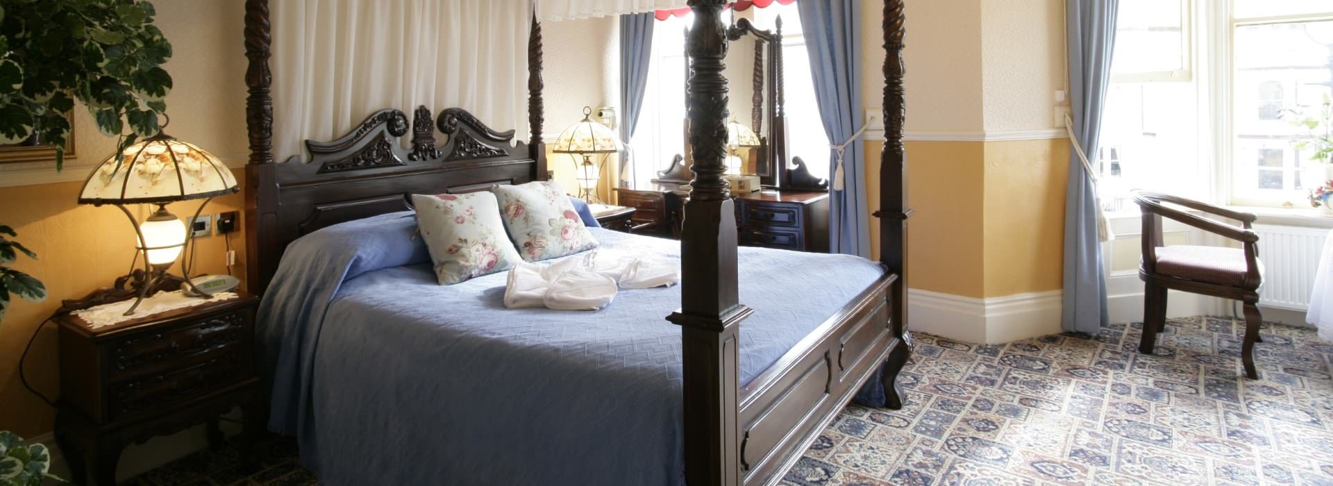 Dark wooden four-post bed with lavendar bedding