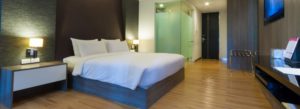 Bedroom with dark wooden paneling, light brown hardwood flooring, and platform bed with white bedding